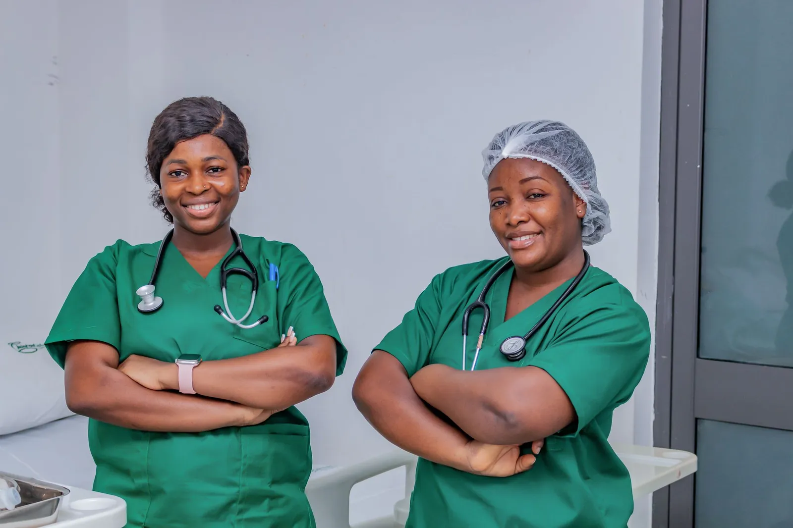 Two nurses in green scrubs in a hospital room